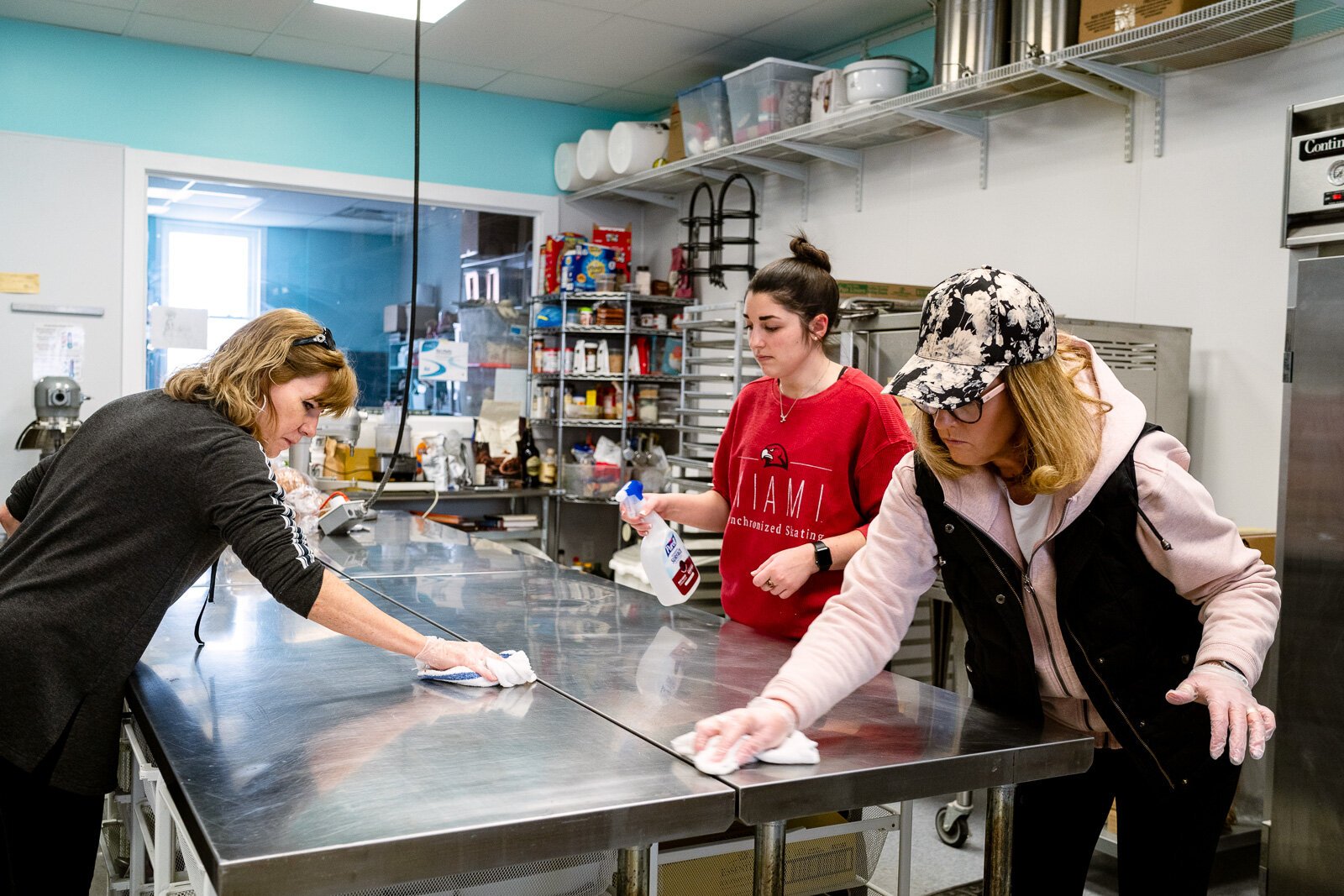Workers sanitize a surface used to make school lunches at Eat More Tea.
