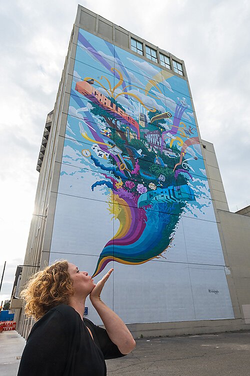 Mary Thiefels of TreeTown Murals in front of their mural at Courthouse Square.