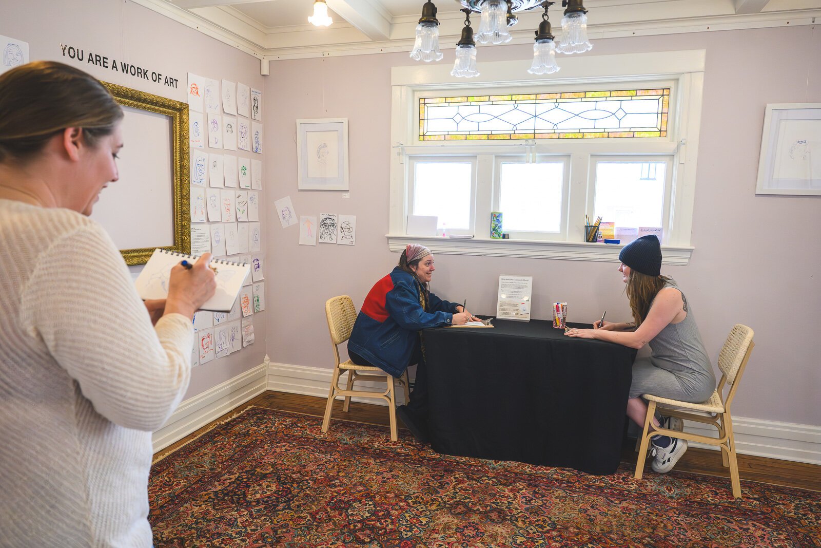 Sarah Nisbett sketching Brittany Slater and Mackenzie Stolzenburg while they draw blind portrits of each other.