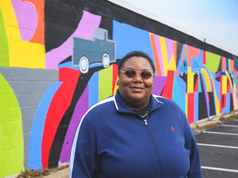 Youth Art Gallery Executive Director T'Onna Clemons in front of the Youth Art Gallery mural at Community Auto Wash.