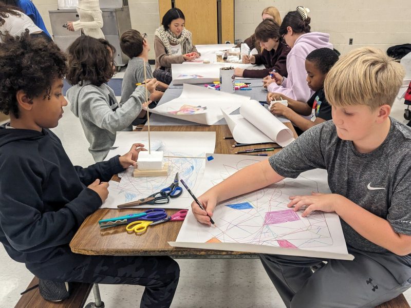 Stamps School students helping YIES students work on artwork for their capstone projects.
