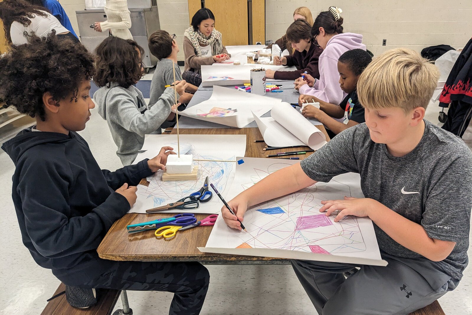 Stamps School students helping YIES students work on artwork for their capstone projects.