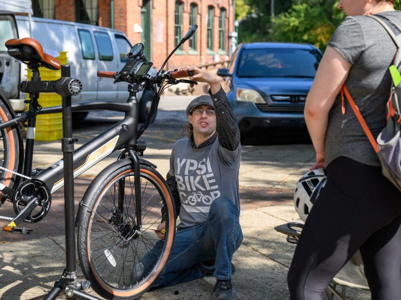 Anthony Lutz repairing a bike at the Ypsi Bike Co-op's booth at Ypsilanti's Depot Town farmers market.
