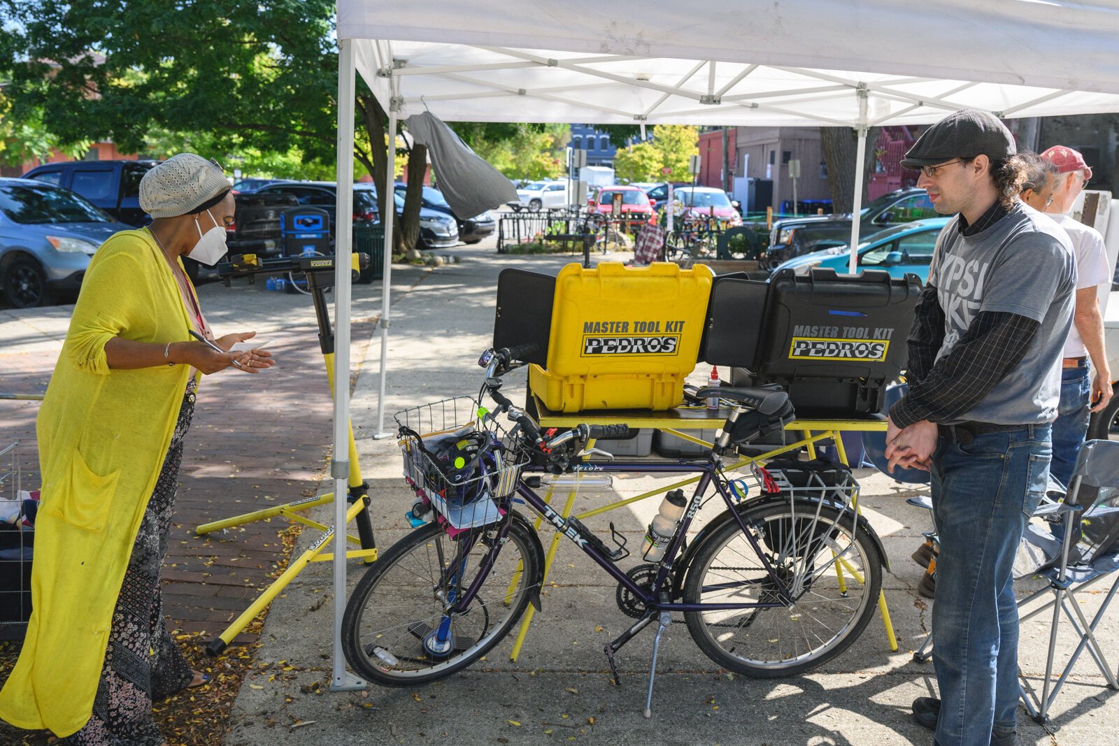 Anthony Lutz repairing a bike at the Ypsi Bike Co-op's booth at Ypsilanti's Depot Town farmers market.