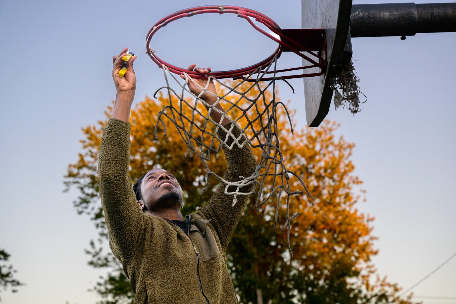 Akintunde Oluwadare replacing a basketball net at West Willow Park.