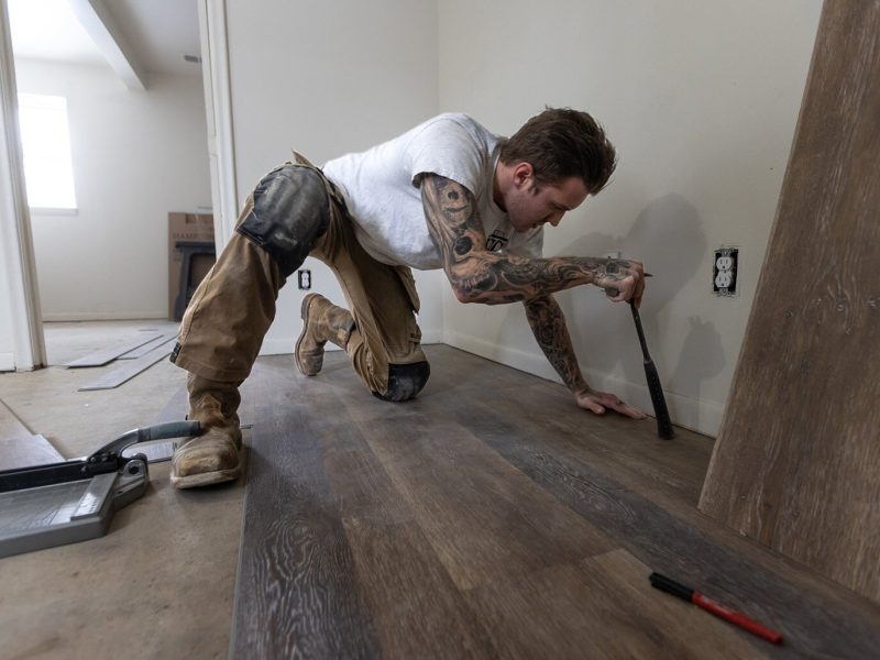 Gavin Witten, an Ypsilanti-based contractor, lays flooring during a recent remodel project at one of Yarrow's properties. Yarrow works only with local tradespeople.