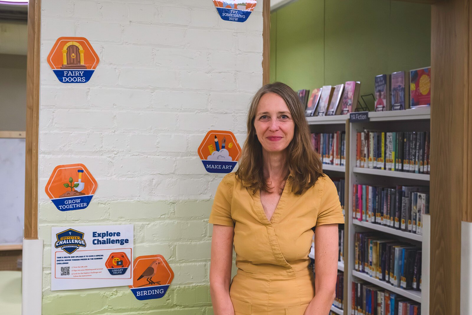 Jodi Krahnke next to Summer Challenge materials at YDL's Michigan Avenue branch.