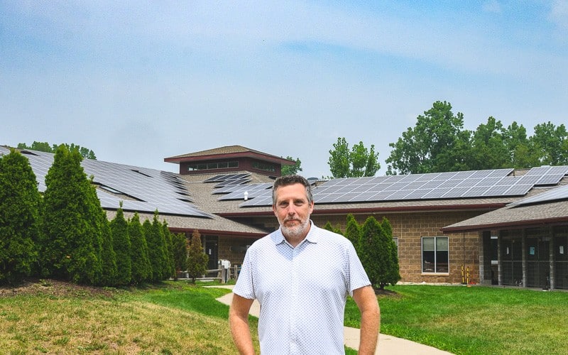 Humane Society of Huron Valley CFO Jonathan Trevathan stands in front of new solar panels at the Humane Society's offices.