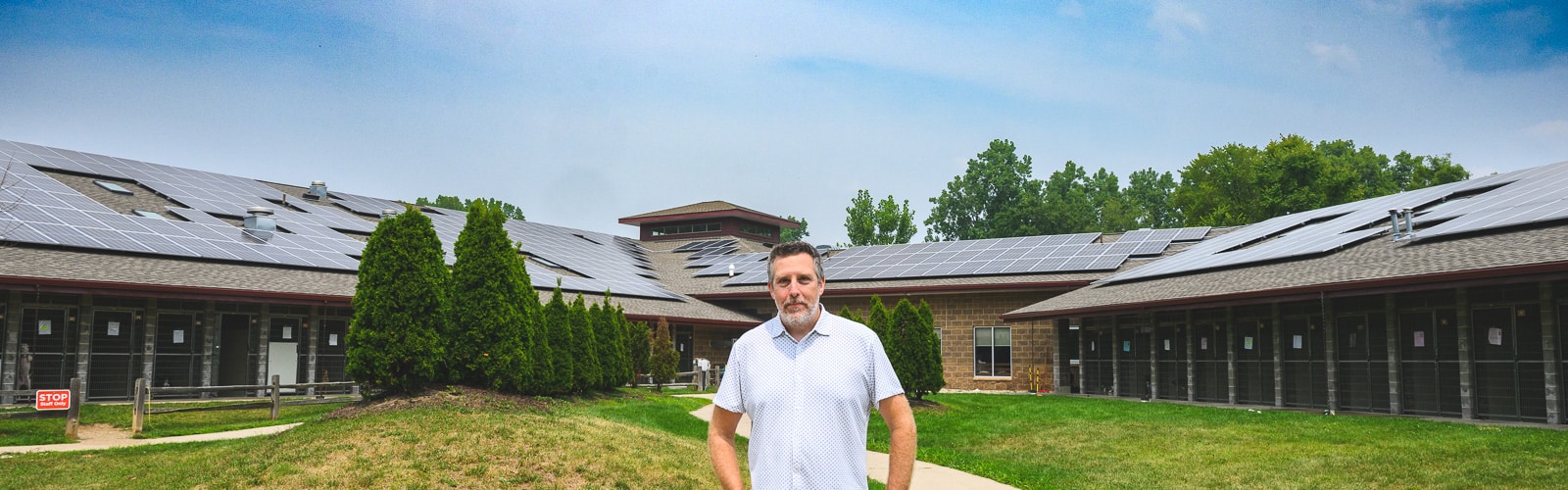 Humane Society of Huron Valley CFO Jonathan Trevathan stands in front of new solar panels at the Humane Society's offices.