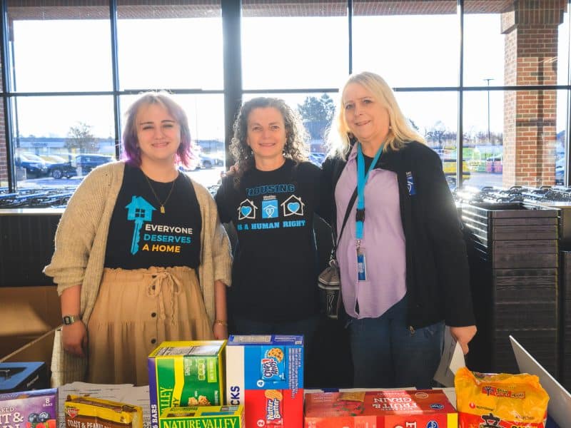 Shelter Association of Washtenaw County staffers Alondra Burne, Nicole Adelman, and Dawn Gemler at a "Fill That Van!" event, collecting food donations for people experiencing homelessness. The Shelter Association of Washtenaw County is one of nine local organizations that will receive opioid lawsuit settlement funds.