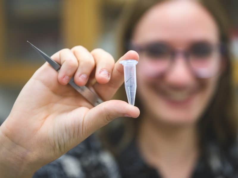 Eastern Michigan University student Avi Dragun holds a vial containing a fiber found in a Peruvian mummy.