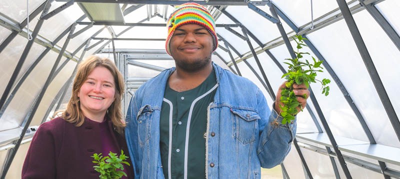 Biology teacher Laurel Wiinikka-Buesser and botany student Elijah Acheampong in the greenhouse at Ypsilanti Community High School.
