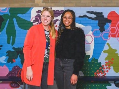 Artists Krista Skytta and Avery Williamson in front of their mural at Mitchell Elementary School in Ann Arbor.