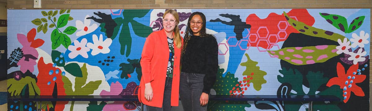 Artists Krista Skytta and Avery Williamson in front of their mural at Mitchell Elementary School in Ann Arbor.