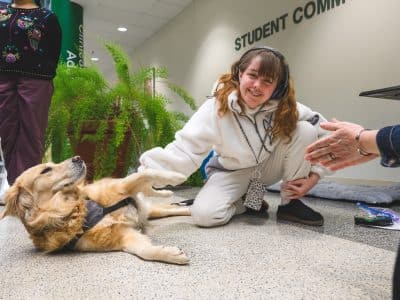 Tinker the facilities dog with Eastern Michigan University student Elena Quinonez.