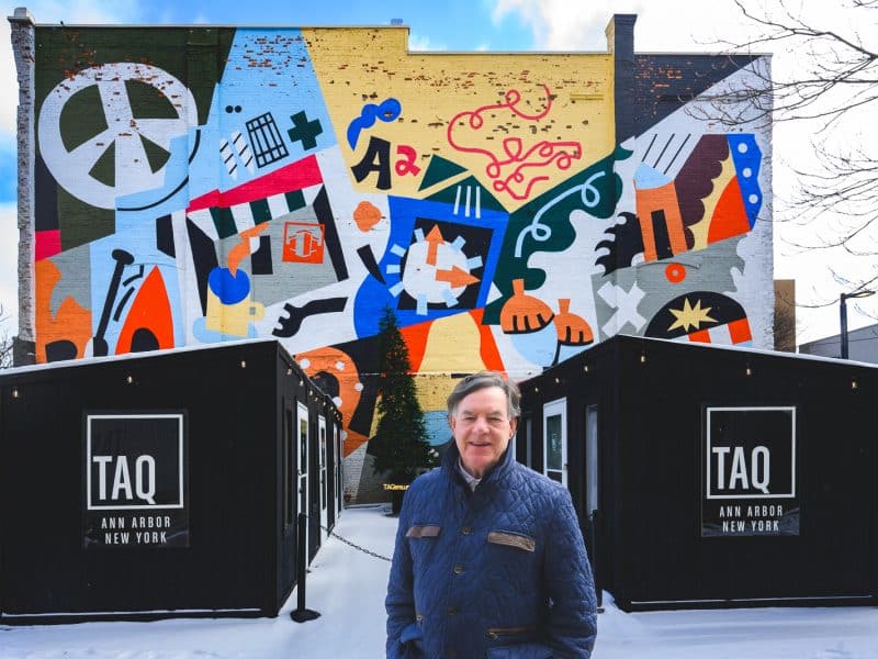 Edward Shaffran in front of the mural on downtown Ann Arbor's Pretzel Bell building, which he owns.