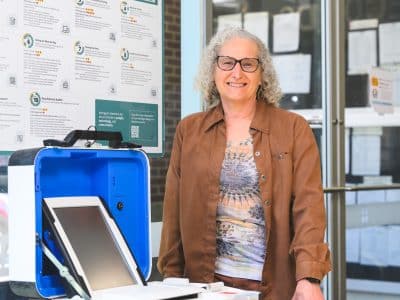 Washtenaw County Director of Elections Rena Basch stands next to a voting machine.