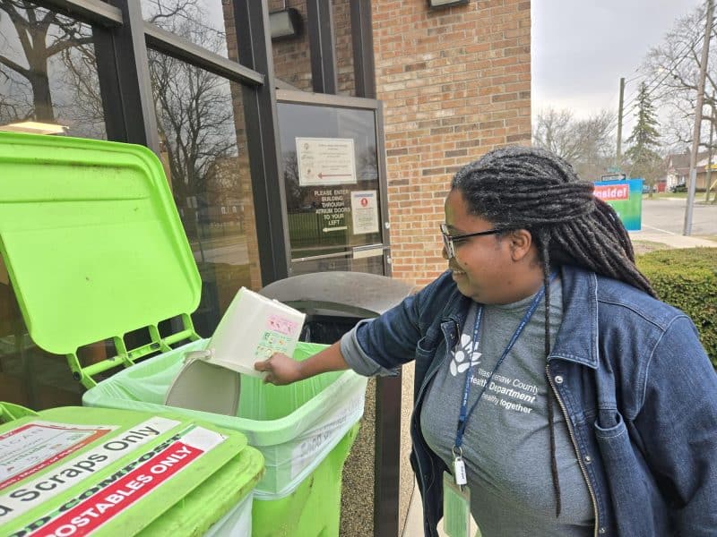 Washtenaw County staff demonstrate a food scrap collection bin.