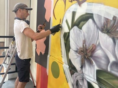 Artist Brandon Gaia Marshall works on a mural in the Ann Ashley parking structure in Ann Arbor, which is intended to help guide the way between the structure and the Ann Arbor Farmers Market.